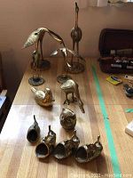 Overall view of all brass bird and fish figurines displayed on wooden surface