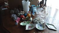 Wide view of all ceramic flowers, stone eggs, plates, and additional decor items on table.