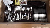 Top view of the flatware set showing knives neatly lined in a wooden chest along with forks, spoons, and serving utensils.