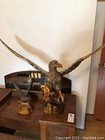 Two wood carved eagles on wooden furniture, large eagle with wings spread wide and smaller eagle beside it