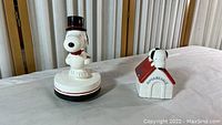 Photo showing both Snoopy music boxes: one with rotating top hat and one on doghouse marked Superbeagle.