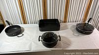 Full set of cookware displayed on table including 3 Circulon frying pans and 1 Kirkland roaster.
