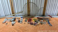 Wide shot of fishing nets, hooks, bobbers, sinkers and other fishing accessories arranged on an orange towel showing overall lot contents.