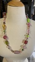 Close-up front view of the vintage multi-color glass bead necklace displayed on mannequin bust.