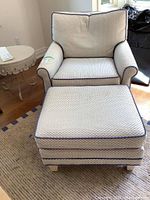 Front view of upholstered chair and ottoman set on area rug