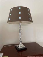 Front view of the modern table lamp showing silver base and brown shade with blue squares