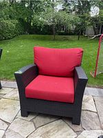 Front view showing brown wicker frame and red seat and back cushions.