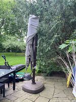 Overall view of closed taupe canopy and brown metal frame on patio with weighted base