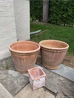 Three planters on stone patio against white brick wall