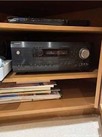 Front full view of Integra receiver placed in wooden shelving, showing main display and controls.