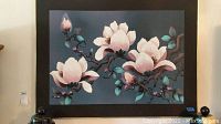 Photo of framed art print with large white magnolia flowers on dark blue background.