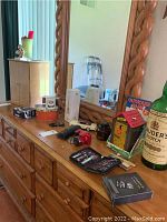 Wooden dresser with carved framed mirror, jewelry box, Canon camera, manicure sets, bank toy, voice recorder and other small items on top.