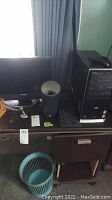 Photo of desk with X2gen monitor, HP tower, keyboard, speaker, and trash bin.