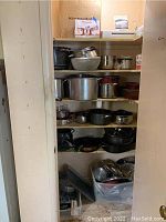 View of shelves with pots, mixing bowls, bakeware, and tubs of smaller items
