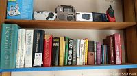 Shelf with radios, clock radio, walkie-talkie, and books including dictionaries and encyclopedias