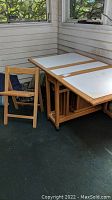 Folded wooden table with four foldable chairs around it on a porch.