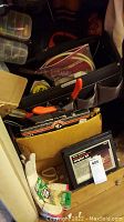 View of carrying case with assorted hand tools like pliers and boxes with hardware inside storage area