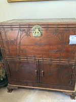 Front view of teak storage cabinet with carved bamboo design, visible cabinet doors and brass hardware latch