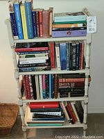 Front view of the wooden book case filled with a variety of books on four shelves.