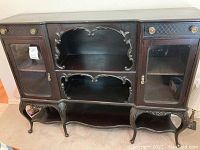 Front view of entire cabinet showing drawers, glass-front doors, open shelves and ornate carved legs