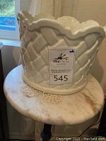 Marble top and ceramic vessel on top of plant stand visible, showing scale and material.