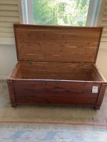 Photo showing open cedar chest with hinged lid revealing fully lined cedar interior and lock mechanism without key.