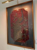 Front view of framed artwork hanging on wall under picture light