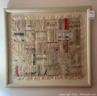 Full view of the framed vintage quilt piece hung on the wall showing the ivory frame and quilt patchwork.
