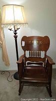 Full view of vintage oak rocking chair next to floor lamp with fabric shade