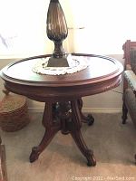 Oval ornate wood end table with smoked glass lamp and crocheted doily on top