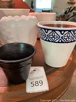 Wide view of assorted pottery pots including a black glossy Red Wing pot, a white pot with blue decorative pattern, and white swirled pot