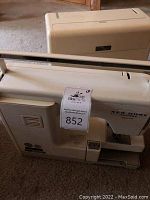 Photo of the side and top angle of New Home Memory Craft 8000 sewing machine with carrying case visible on top.