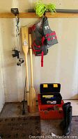 Photo showing whole lot including Shakespeare 606 outboard motor, two wooden Cavpro paddles, XL Mystic life jacket, size 8 rubber boots, and orange tackle boxes on ground.