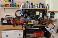 Workbench area with various tools including Skil saw, screwdrivers, nails, and crafting items arranged on a pegboard and shelves.