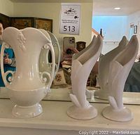 Front view of the three ivory vases, showing two Van Briggle bud vases and one Abingdon vase with handles and ornamental details.
