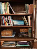 Front view of wooden bookcase shelves filled with assorted vintage books of different sizes and colors.