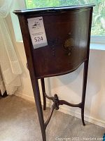 Photo of the vintage wooden plant stand showing dark wood paneling with carved decorative accents and slender legs