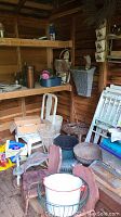 Photo showing shelves with various pots, chairs, wicker baskets, and garden accessories in a wooden shed