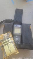Fluke 41B Power Harmonic Analyzer held upright in black carrying case with zipper open, displaying front panel and screen
