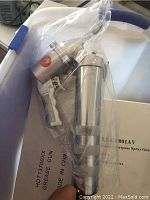 White and blue multipurpose spray gun with aluminum reservoir sealed in plastic on top of tote