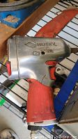 Side view of red and silver Husky impact wrench with logo and red trigger