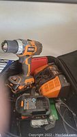 Ridgid cordless drill with two batteries, charger, drill bits, and safety glasses in a bag.
