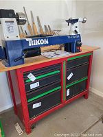 Lathe mounted on rolling tool cabinet with wood top in corner of room