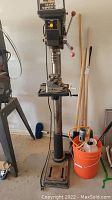Full view of the Sears Craftsman drill press showing the metal base, column, working table with a vise, and the control head with three handles for adjustment.
