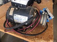 Sears Craftsman black capacitor star AC motor with wiring and attached light switch on wooden surface.