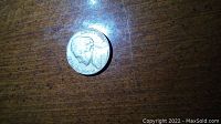 Obverse photo showing portrait of John F. Kennedy and inscriptions "In God We Trust" and "Liberty" with letters very close to the edge.