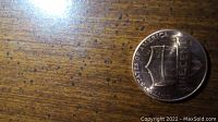 Photo shows a 2021 D Mint penny with shield reverse design on a wooden surface.