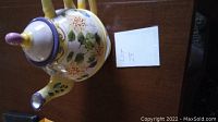 Top view of the ceramic teapot showing floral patterns and purple lid with yellow handle