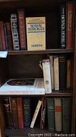 Books arranged on wooden shelves showing a variety of titles and worn condition.