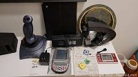 Overhead view showing Logitech joystick, Dymo label maker, label maker power adapters, and two iPod Shuffle units with manuals